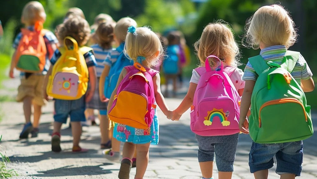 Schoolchildren wearing backpacks as they walk in a line down a path that goes through the trees
