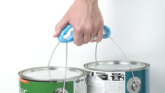 Woman's hand holding two paint cans at once using a blue heavy-duty Click & Carry utility handle