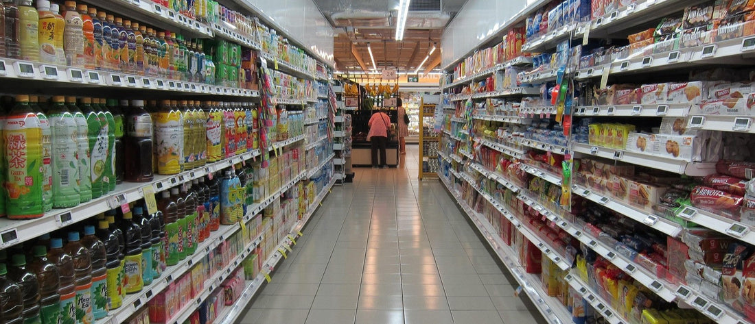 View down a grocery store aisle with a shopper viewing merchandise at the end