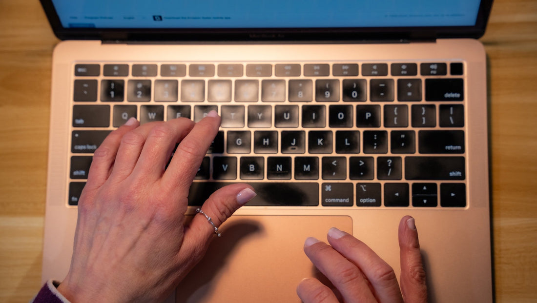 The hands of entrepreneur Kim Meckwood working at her laptop on a wooden desk