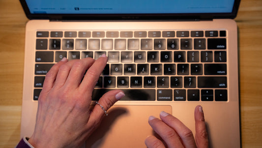 The hands of entrepreneur Kim Meckwood working at her laptop on a wooden desk
