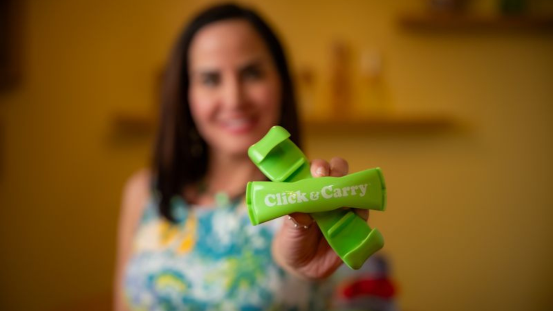 A blurred Kim Meckwood holding a twisted-open green Click & Carry in front of her