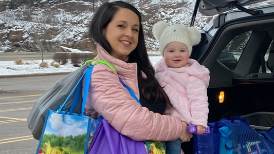 Mother with baby carrying grocery bags over her shoulder