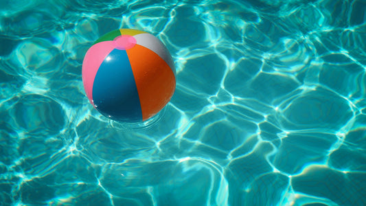 Multicolored beach ball floating in pool water